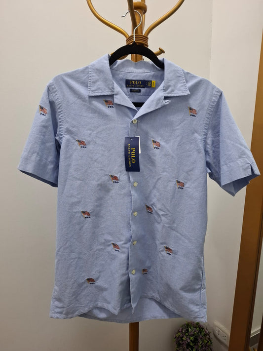 CAMISA MANGA CORTA POLO RALPH LAUREN COLOR CELESTE CON BANDERA DE USA POR TODA LA PRENDA- TALLA S