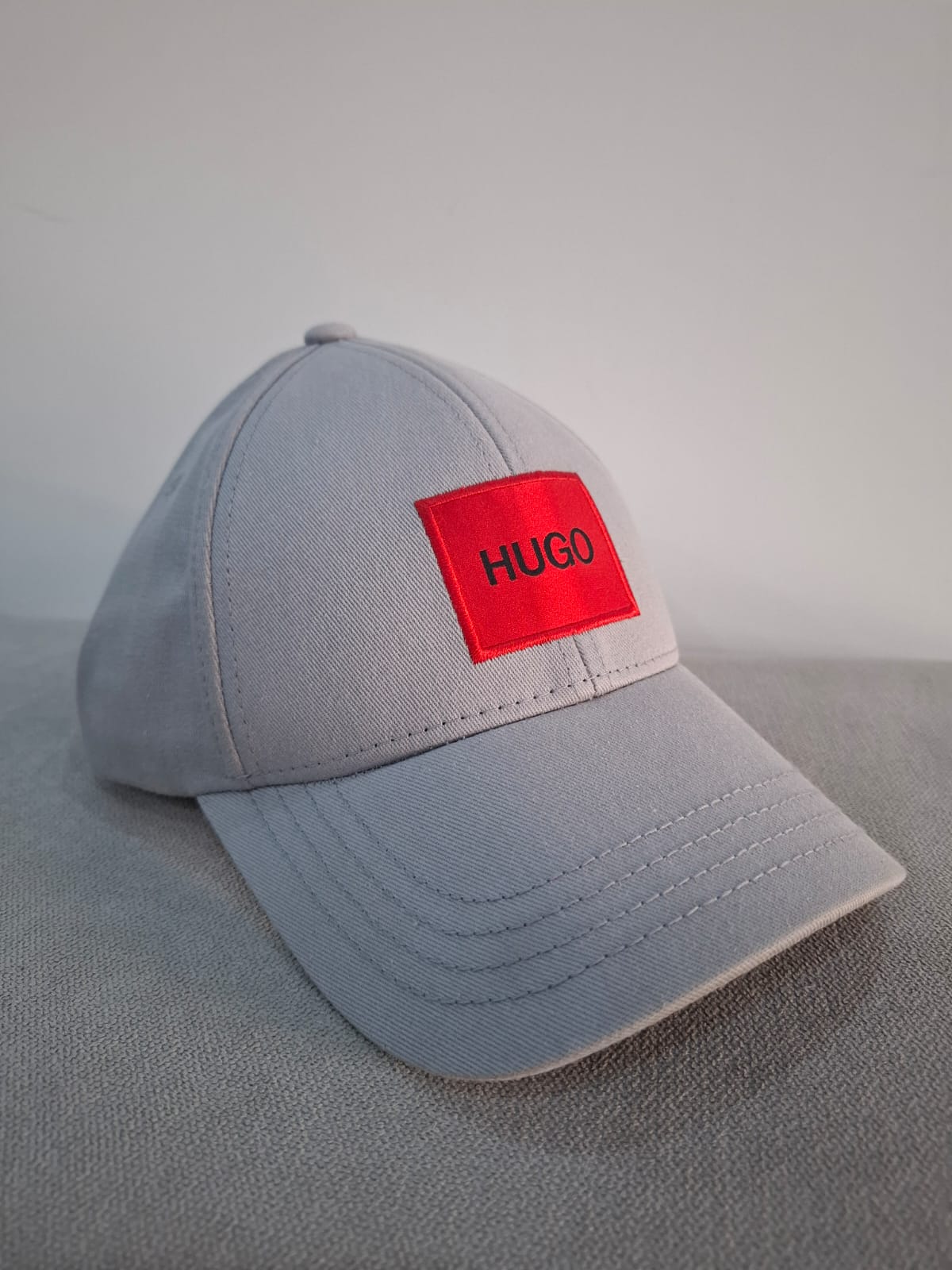 GORRA HUGO BOSS EN COLOR GRIS CON EL LOGO EN ROJO EN LA PARTE DELANTERA